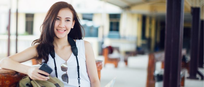 Frau mit Reisetasche und Smartphone