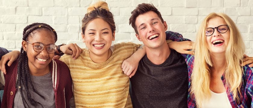 Diverse group of students lies laughing in each other's arms
