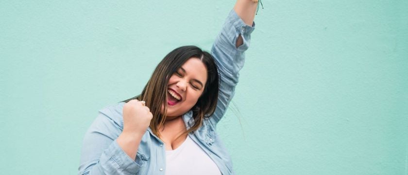 Young woman rejoices with one arm in the air 