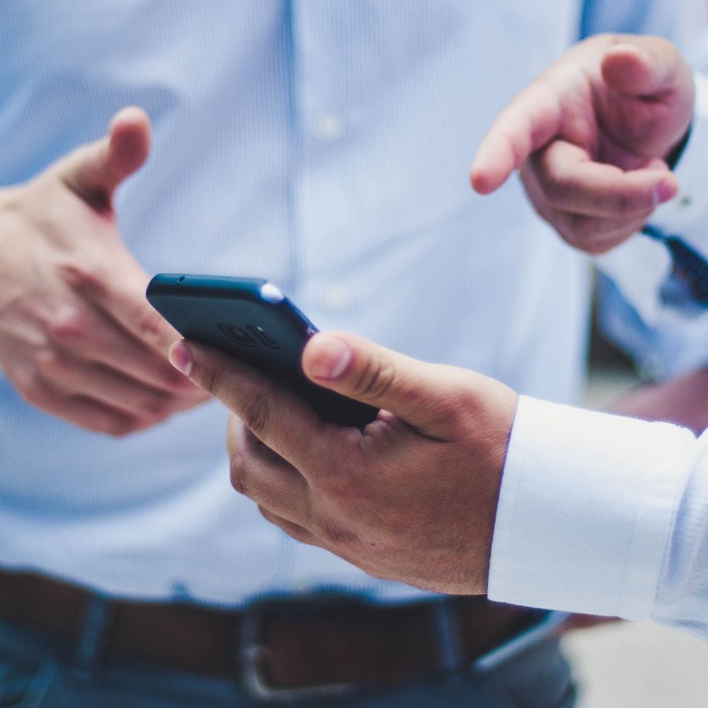 people in business clothes poining at smartphone screen