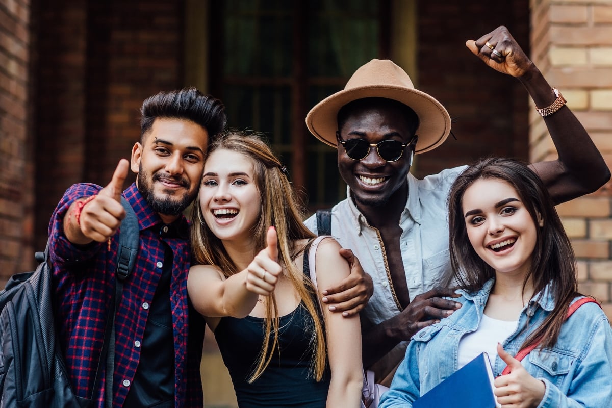 diverse group of friends laughing to the camera with thumbs up