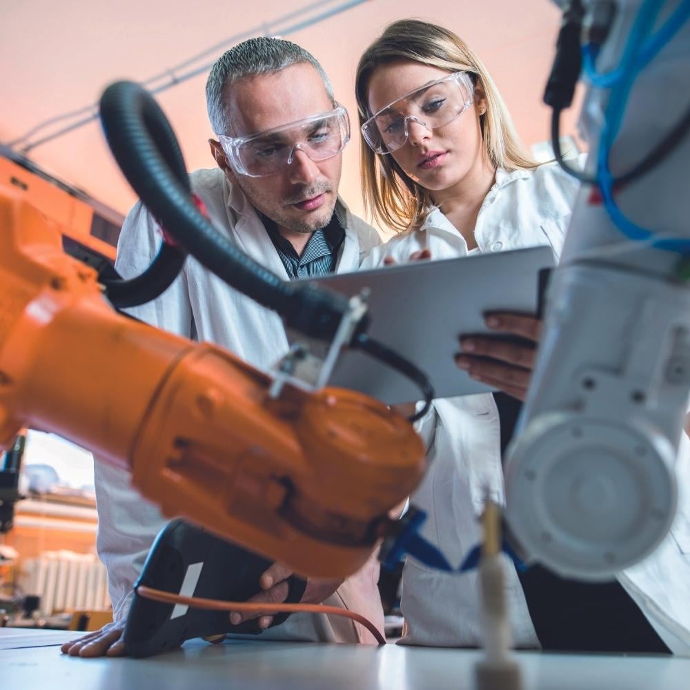 Man and woman in lab clothes at a robot