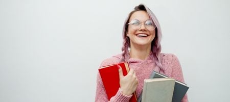 Frau mit pinken Haaren und Büchern im Arm