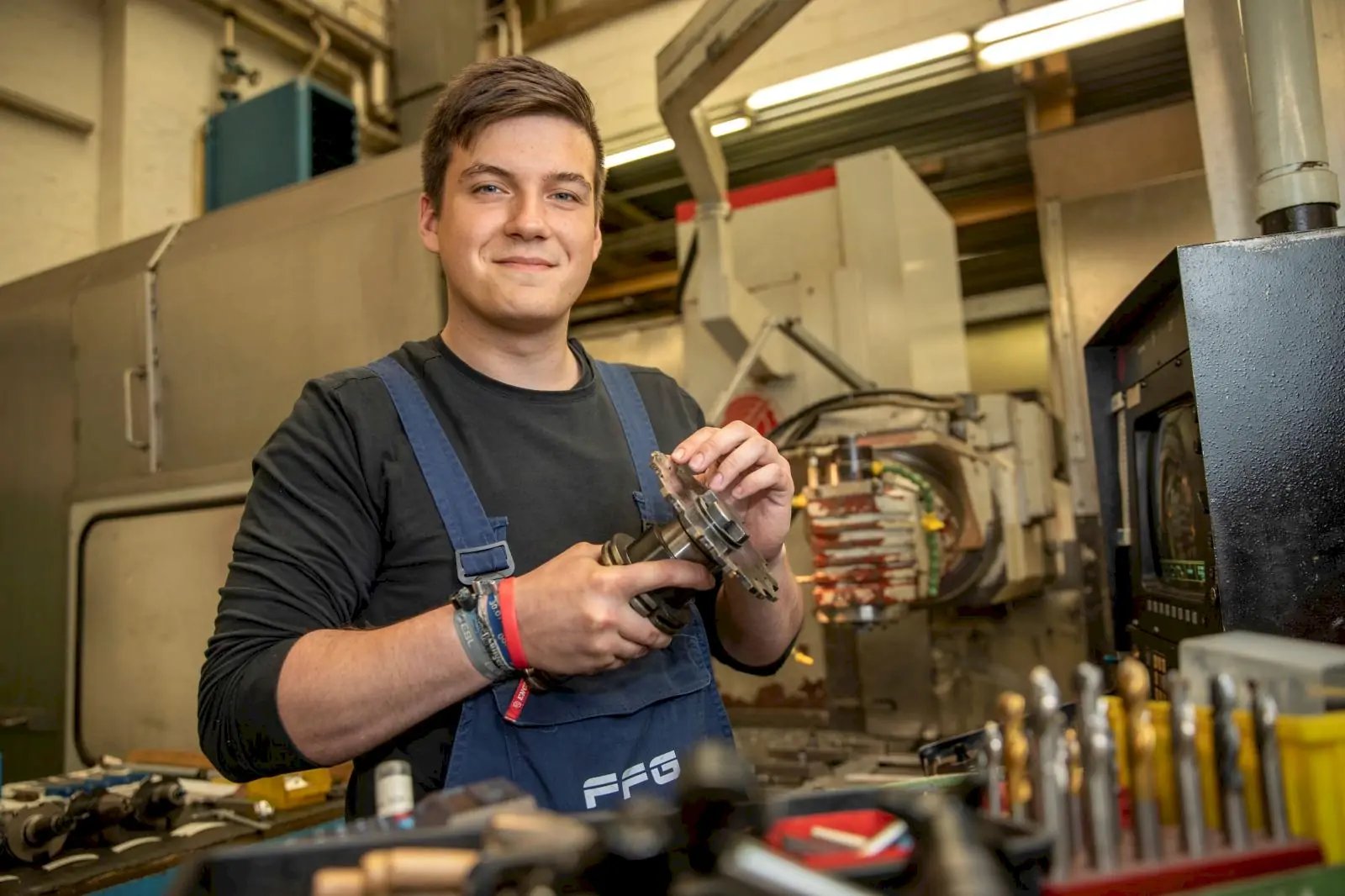 Junger Mann in Blaumann in einer Werkstatt